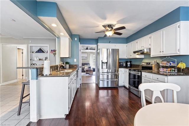 kitchen featuring built in shelves, sink, a kitchen breakfast bar, white cabinets, and appliances with stainless steel finishes