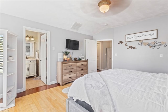 bedroom featuring lofted ceiling, ensuite bathroom, sink, ceiling fan, and light wood-type flooring