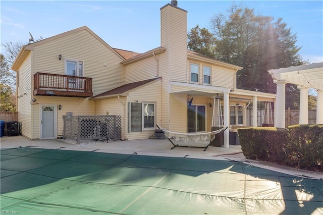 back of house featuring a balcony, a pergola, and a covered pool