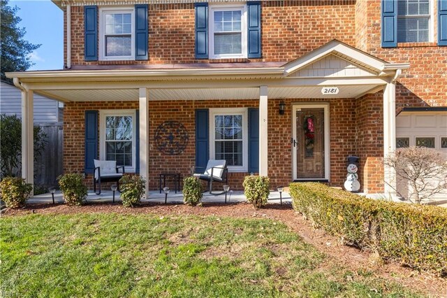 view of exterior entry featuring a yard and a porch