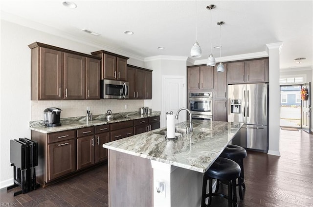 kitchen featuring sink, hanging light fixtures, stainless steel appliances, a kitchen island with sink, and dark brown cabinets