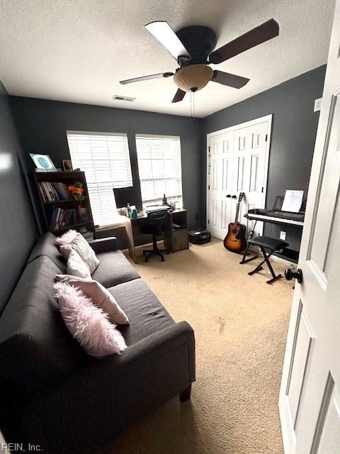 living room with carpet flooring, ceiling fan, and a textured ceiling