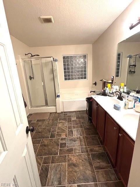 bathroom with vanity, a textured ceiling, and independent shower and bath