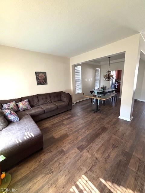 living room featuring a chandelier and dark wood-type flooring