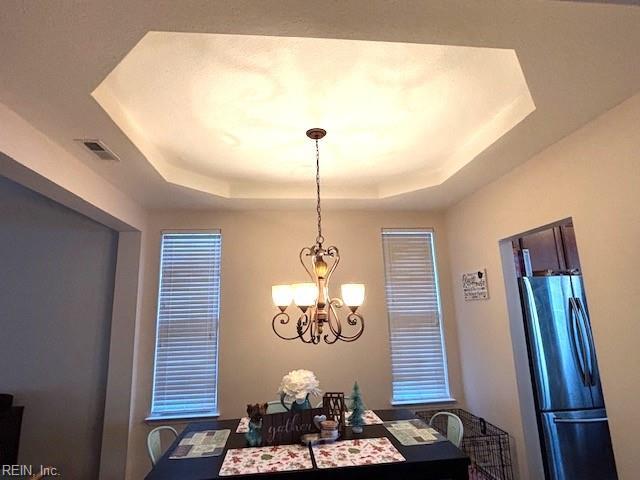 dining area featuring a tray ceiling and a notable chandelier