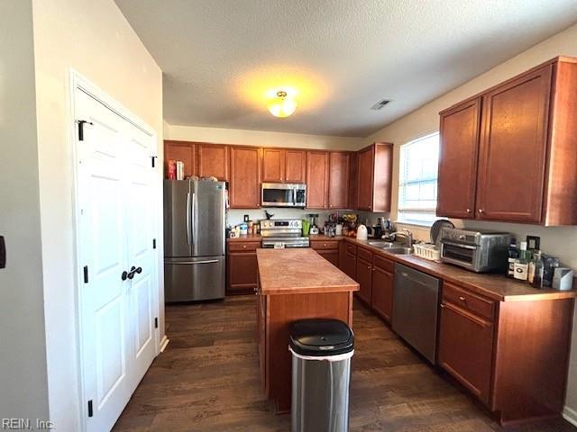 kitchen featuring sink, a center island, dark hardwood / wood-style floors, and appliances with stainless steel finishes