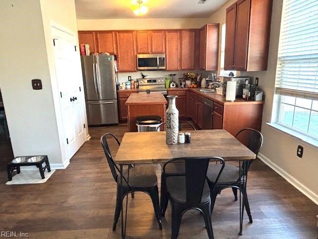 kitchen with dark wood-type flooring, a center island, stainless steel appliances, and sink