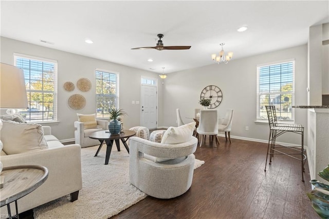 living room with ceiling fan with notable chandelier, plenty of natural light, and dark wood-type flooring