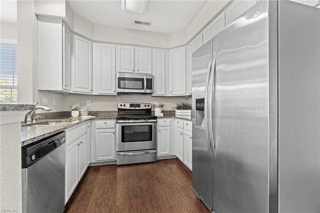 kitchen with white cabinetry, sink, light stone countertops, dark hardwood / wood-style flooring, and appliances with stainless steel finishes