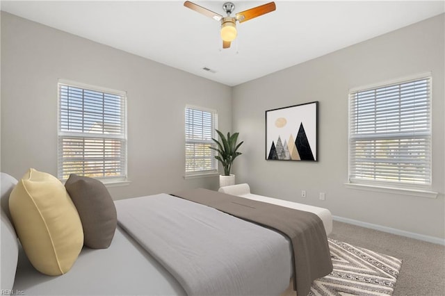 carpeted bedroom featuring multiple windows and ceiling fan