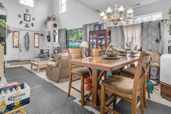 dining area featuring a high ceiling, plenty of natural light, and a notable chandelier