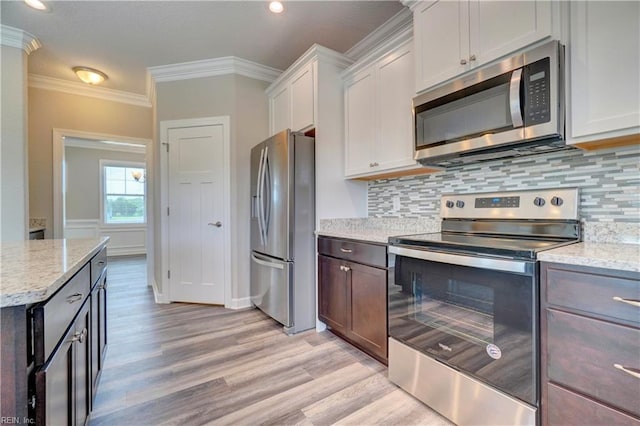 kitchen featuring light stone counters, crown molding, white cabinets, and stainless steel appliances