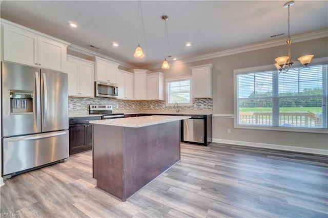 kitchen featuring a center island, stainless steel appliances, an inviting chandelier, and hanging light fixtures