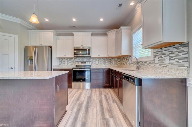 kitchen with light stone countertops, white cabinetry, sink, crown molding, and appliances with stainless steel finishes