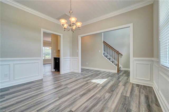 empty room with crown molding, a chandelier, and wood-type flooring