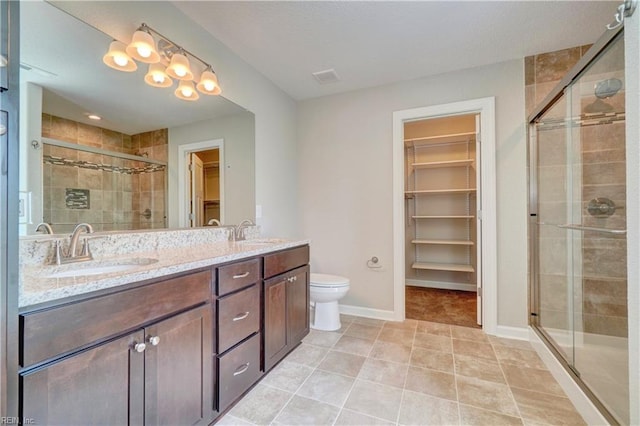 bathroom with tile patterned flooring, vanity, toilet, and walk in shower