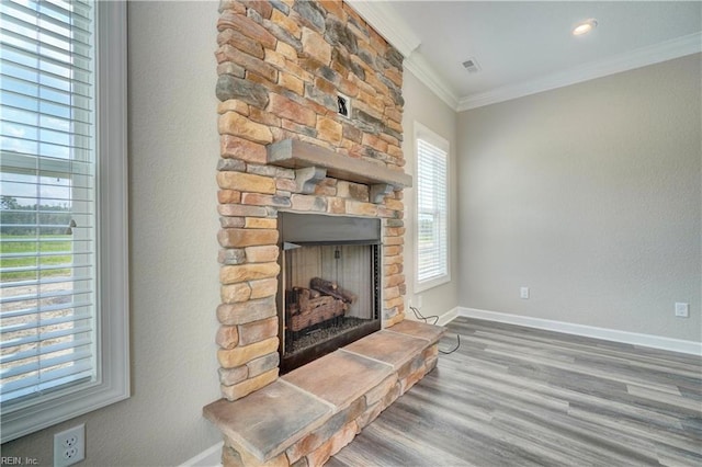 living room with hardwood / wood-style flooring, a stone fireplace, and crown molding