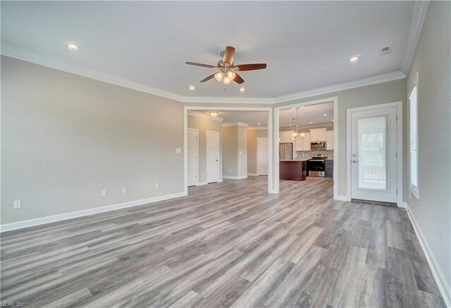 unfurnished living room featuring ceiling fan with notable chandelier, light wood-type flooring, and crown molding