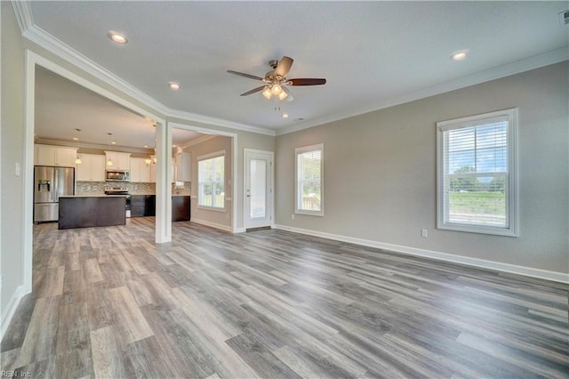 unfurnished living room with a wealth of natural light, crown molding, hardwood / wood-style floors, and ceiling fan