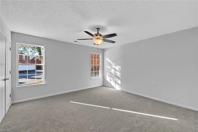 empty room featuring a textured ceiling, carpet floors, a wealth of natural light, and ceiling fan