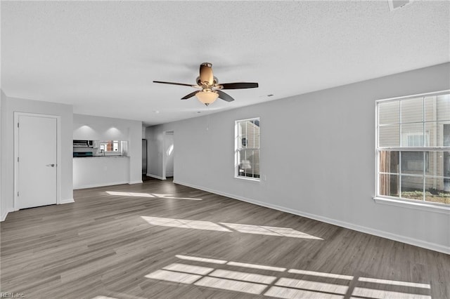 unfurnished living room featuring hardwood / wood-style flooring, ceiling fan, and a textured ceiling