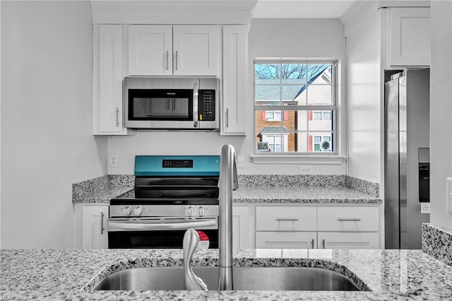 kitchen with white cabinets, appliances with stainless steel finishes, and light stone counters