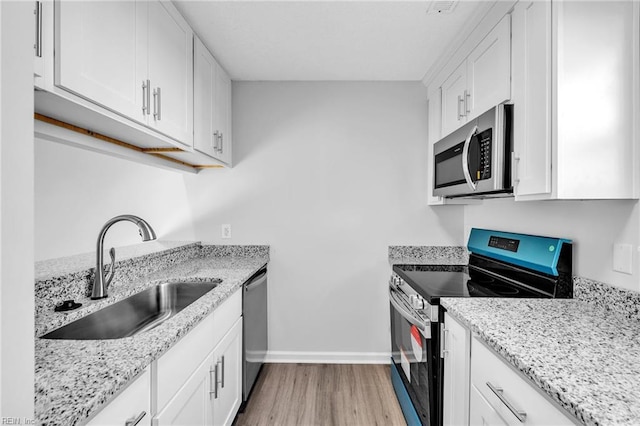 kitchen with light hardwood / wood-style floors, white cabinetry, sink, and appliances with stainless steel finishes