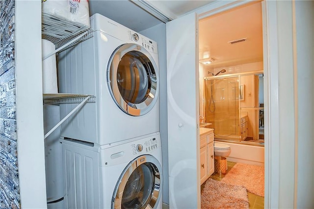 laundry room featuring tile patterned floors and stacked washer / drying machine