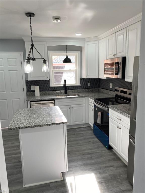 kitchen featuring sink, appliances with stainless steel finishes, decorative light fixtures, light stone counters, and white cabinetry