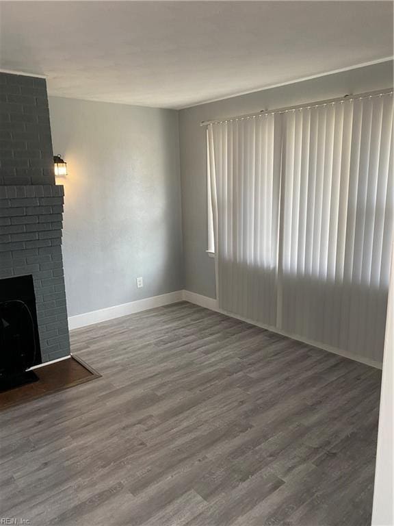 unfurnished living room featuring wood-type flooring and a brick fireplace