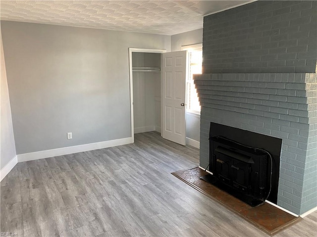 unfurnished living room featuring a wood stove, wood-type flooring, and a textured ceiling