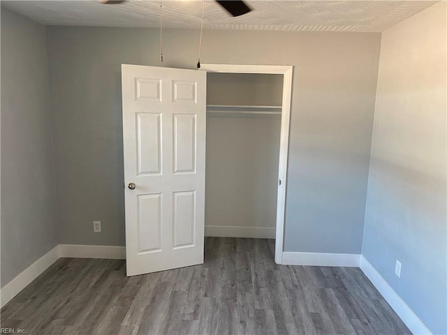 unfurnished bedroom with a textured ceiling, dark wood-type flooring, and a closet