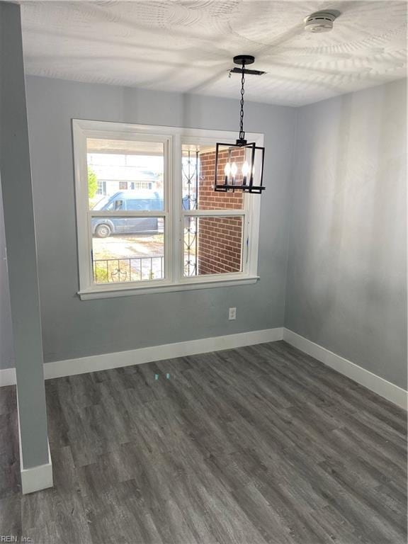 unfurnished dining area with dark wood-type flooring and an inviting chandelier