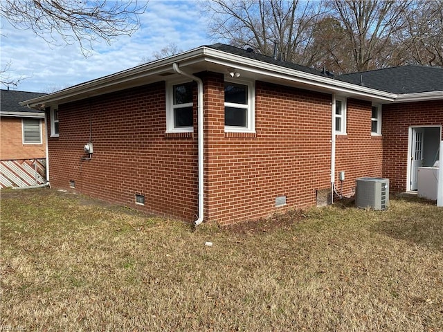 view of side of property featuring central air condition unit and a yard