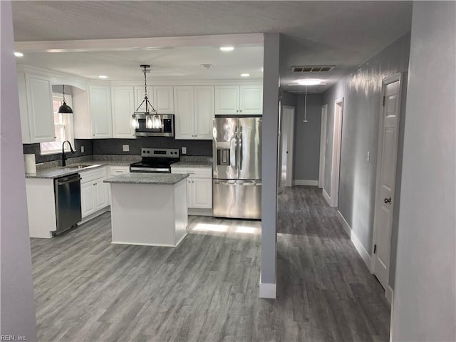 kitchen featuring stainless steel appliances, sink, white cabinetry, a kitchen island, and hanging light fixtures