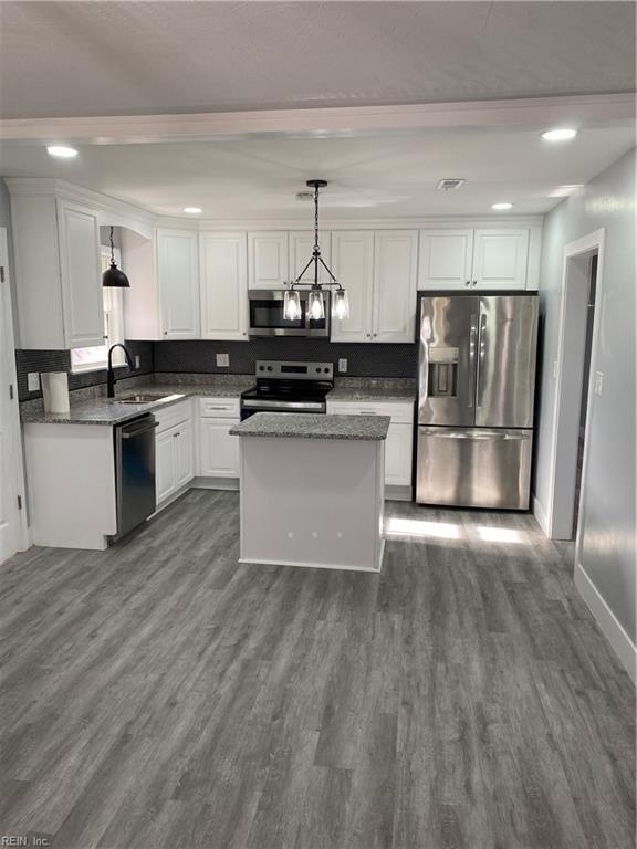 kitchen with sink, dark wood-type flooring, decorative light fixtures, white cabinets, and appliances with stainless steel finishes