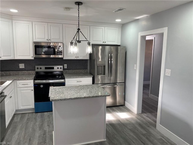 kitchen with a kitchen island, light stone counters, pendant lighting, white cabinets, and appliances with stainless steel finishes