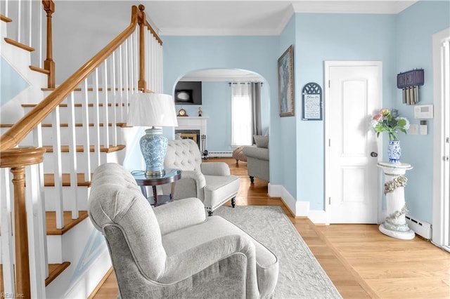 interior space featuring wood-type flooring, a baseboard radiator, and crown molding