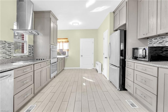 kitchen with white appliances, ventilation hood, light stone counters, and plenty of natural light