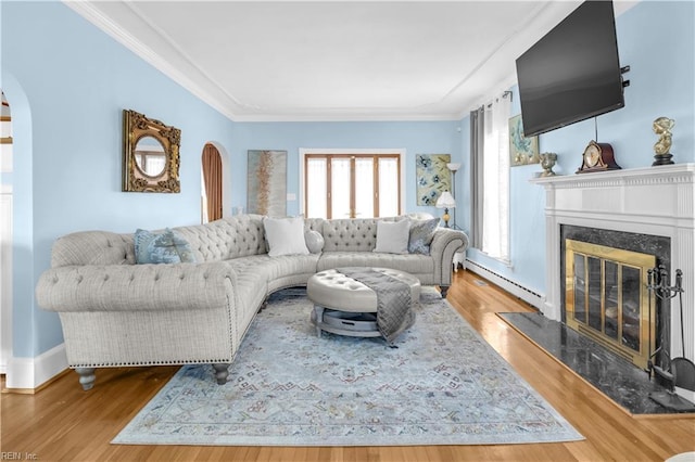 living room with crown molding, hardwood / wood-style floors, a high end fireplace, and a baseboard heating unit