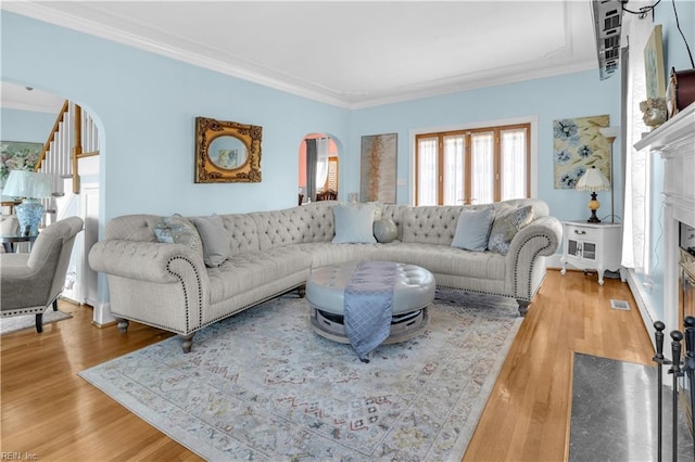 living room featuring crown molding, a fireplace, and wood-type flooring