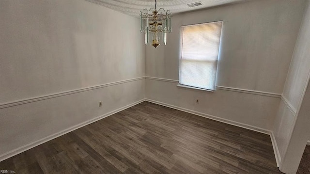 spare room featuring a notable chandelier and dark hardwood / wood-style floors