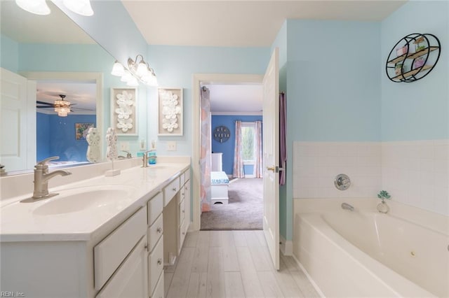 bathroom with a tub to relax in, ceiling fan, vanity, and wood-type flooring