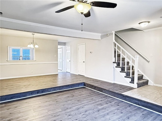 foyer entrance with hardwood / wood-style flooring, ceiling fan with notable chandelier, and ornamental molding