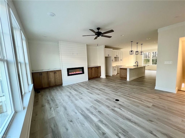 unfurnished living room featuring ceiling fan, light hardwood / wood-style floors, sink, and a fireplace
