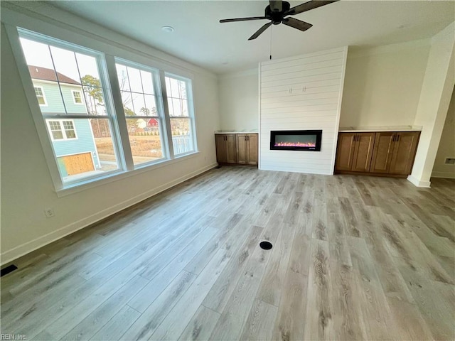 unfurnished living room featuring ceiling fan, light wood-type flooring, and a fireplace