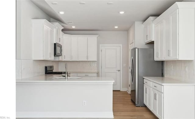 kitchen with kitchen peninsula, sink, white cabinets, and appliances with stainless steel finishes