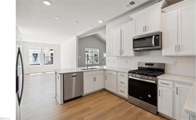 kitchen featuring sink, appliances with stainless steel finishes, plenty of natural light, white cabinetry, and kitchen peninsula