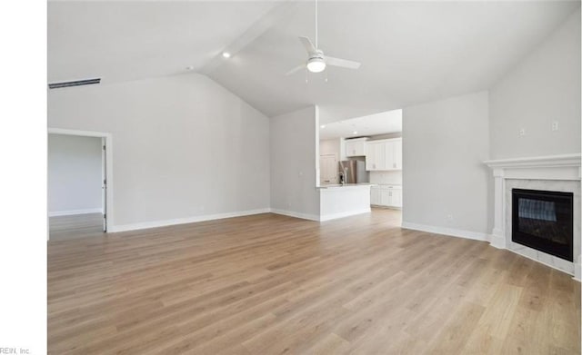 unfurnished living room with a high end fireplace, light wood-type flooring, vaulted ceiling, and ceiling fan