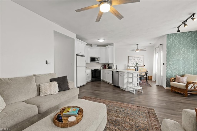 living room featuring ceiling fan, sink, and dark wood-type flooring